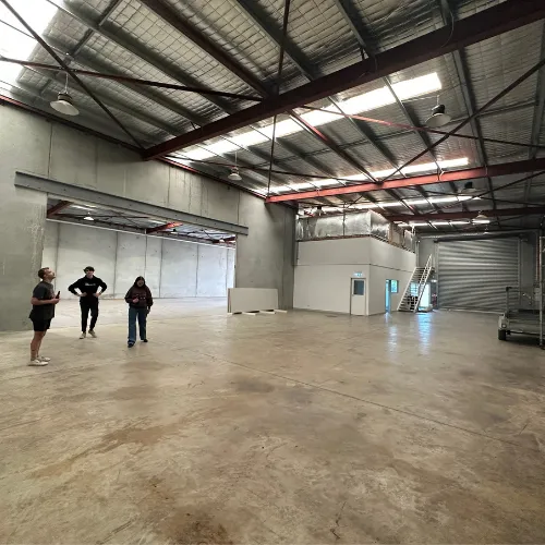 Billy and friends standing in an empty warehouse after business sale, marking the end of a successful journey